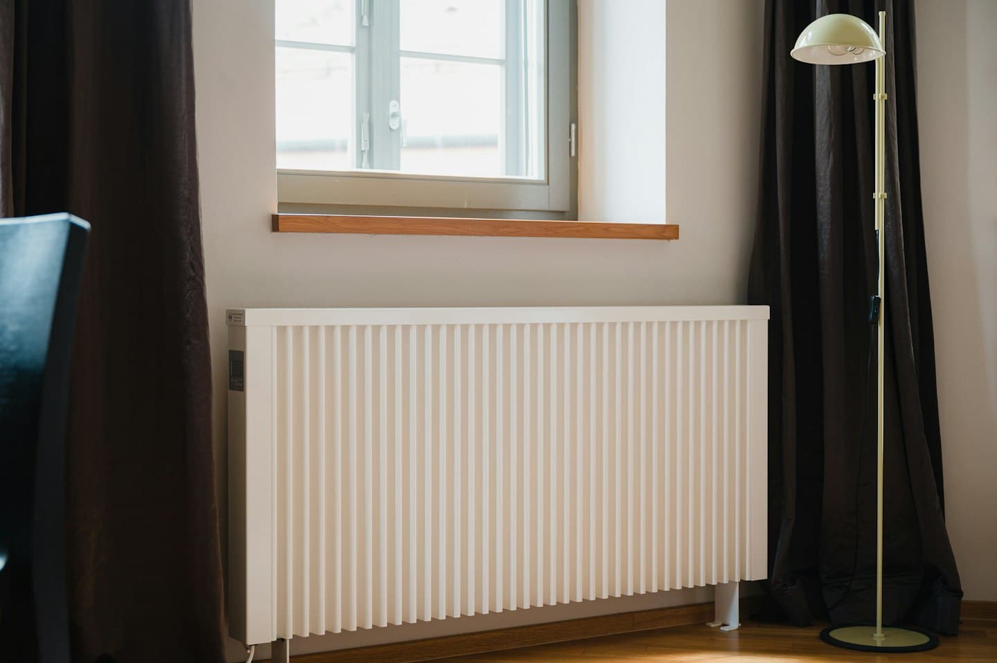 Pencere önünde ahşap pervazlı modern beyaz radyatör.